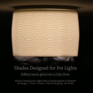 May include: Cream-colored pot light shade with a wave pattern. The shade is cylindrical with a gold-colored trim. Text on the image reads "Shades Designed for Pot Lights" and "Diffuse harsh glare into a Cozy Glow."