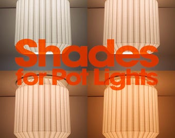 Könnte beinhalten: Vier weiße, plissierte, zylindrische Lampenschirme für Einbaustrahler, die jeweils eine andere Farbtemperatur von kaltweiß bis warmgelb aufweisen, mit dem orangefarbenen Text Shades for Pot Lights in der Mitte überlagert.