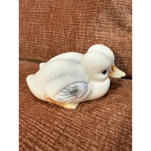 Może przedstawiać: Zestaw trzech ceramicznych kubków z nakrapianym, matowym wykończeniem. Kubki są w odcieniach kremu, jasnoszarym i ciemnoszarym. Każdy kubek ma prosty, minimalistyczny design i zaokrąglony uchwyt.
