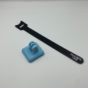 May include: A light blue GoPro mount with a black velcro strap that says "FAVORITE ONE" on it.
