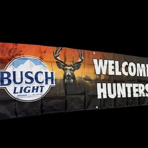 Może przedstawiać: Czarno-pomarańczowy baner z napisem "Busch Light" w niebieskim kółku i napisem "Welcome Hunters" w kolorze białym. Na tle widoczny jest jeleń z porożem.