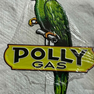以下が含まれることがあります： 緑色のオウムが枝にとまっているヴィンテージの金属看板。看板は黄色の背景に「POLLY GAS」の文字が黒色で書かれています。オウムは赤とオレンジ色のくちばしをしています。装飾品です。