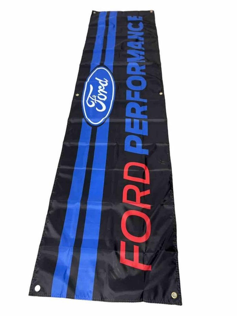 May include: A black banner with the words "FORD PERFORMANCE" in red letters and a blue oval with the word "Ford" in white letters. The banner has two blue stripes.