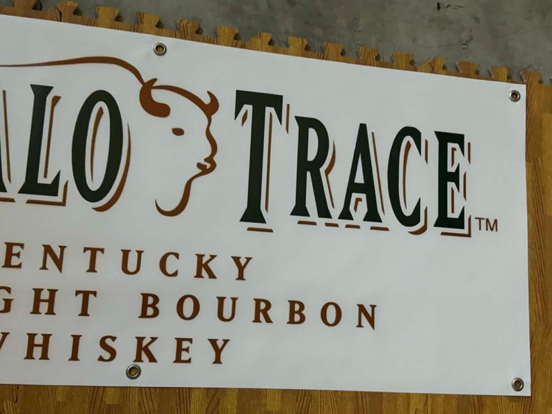 May include: White banner with the words "BUFFALO TRACE" in large, dark green letters with a brown buffalo head logo. Below, the text reads "KENTUCKY STRAIGHT BOURBON WHISKEY".