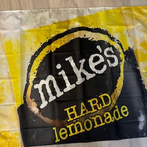 May include: A yellow and black flag with the text "Mike's Hard Lemonade" in a white circle on a black background.