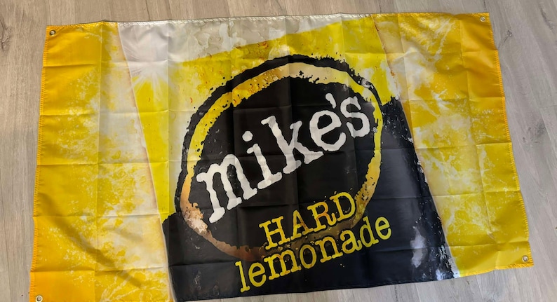 May include: A yellow and black flag with the text "Mike's Hard Lemonade" in a white circle on a black background.