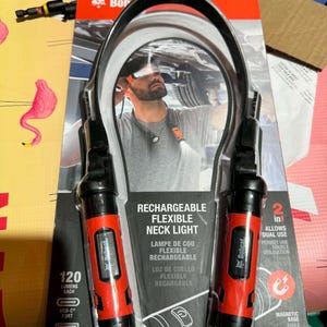 May include: A Bobcat brand rechargeable flexible neck light in retail packaging. The device features two red and black cylindrical light units connected by a flexible band. Text includes Rechargeable Flexible Neck Light, 120 Lumens Each, USB-C Port, 500 mAh Battery, 2 in 1 Allows Dual Use, Magnetic Base, and One Tough Animal.