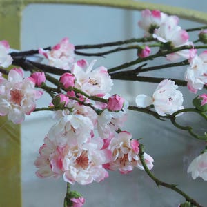 Könnte beinhalten: Nahaufnahme von künstlichen Kirschblütenzweigen mit weißen und rosa Blüten und Knospen. Die Zweige sind braun und grün, mit einigen Blüten in voller Blüte und anderen in Knospen.