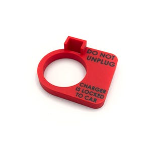 May include: A bright red plastic device with a circular opening and a rectangular section. The text "DO NOT UNPLUG" and "CHARGER IS LOCKED TO CAR" is printed in black. The device is designed to prevent the unplugging of a charger.