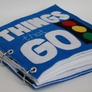 Puede incluir: Un libro de fieltro azul con las palabras "Things that Go" en la portada. El libro tiene un semáforo en la portada con luces rojas, amarillas y verdes.