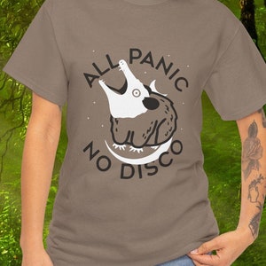 May include: A brown t-shirt with a white graphic of an opossum with the text "All Panic No Disco" printed on it.