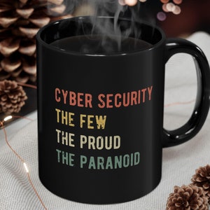 May include: Black coffee mug with white text that reads "Cyber Security The Few The Proud The Paranoid".