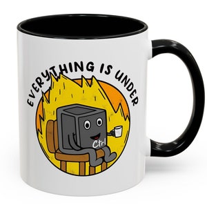 May include: White ceramic mug with a black rim and handle. The mug features a cartoon illustration of a computer with a face and the text "Everything is under Ctrl." The computer is sitting in a chair with flames behind it.