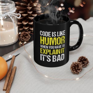 May include: Black coffee mug with white text that reads "Code is like humor when you have to explain it it's bad".
