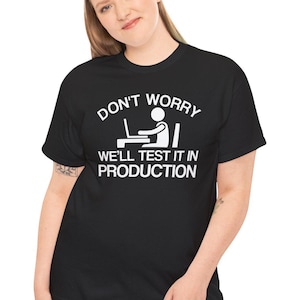 May include: Black t-shirt with white text that reads "Don't worry, we'll test it in production". The text is accompanied by a stick figure illustration of a person sitting at a computer.