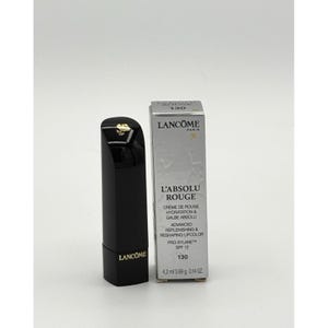 Może przedstawiać: Czarna szminka Lancôme L'Absolu Rouge ze złotym akcentem i pasującym srebrnym pudełkiem. Na pudełku widnieje nazwa produktu, numer odcienia 130 oraz szczegóły dotyczące nawilżającego i modelującego koloru do ust z SPF 12.