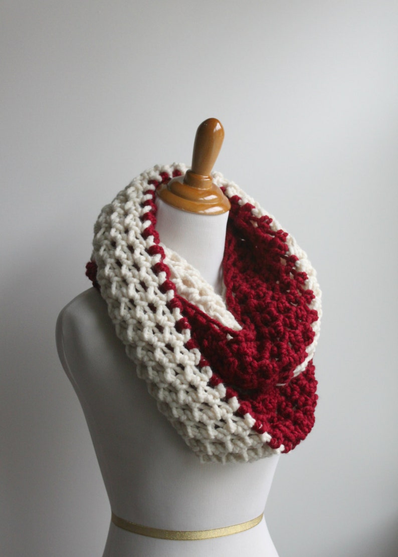 May include: A white and burgundy crocheted infinity scarf. The scarf is made with a chunky yarn and has a simple, yet stylish design.