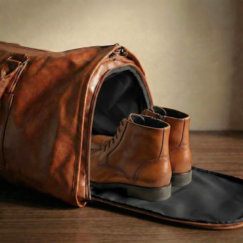 Puede incluir: Una bolsa de viaje de cuero color canela con un compartimento lateral con cierre de cremallera. Dentro del compartimento lateral abierto, hay un par de botas de cuero con cordones del mismo color. La bolsa tiene una textura lisa y oscura.