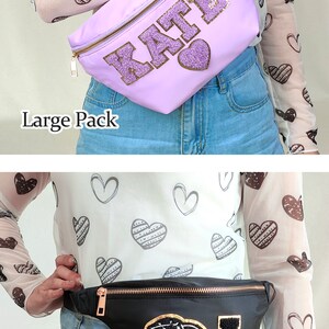 May include: Two fanny packs, one purple with the name "KATE" in gold glitter and one black with a gold glitter cowboy hat and the letter "A". Both fanny packs are worn by a person wearing a white shirt with a brown heart pattern.