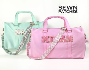 Puede incluir: Dos bolsas de viaje personalizadas con una correa de patrón de chevron. La bolsa de la izquierda es verde claro con el nombre "NA" en letras doradas de purpurina. La bolsa de la derecha es rosa con el nombre "MEGAN" en letras doradas de purpurina. Las bolsas están etiquetadas como "SEWN PATCHES".
