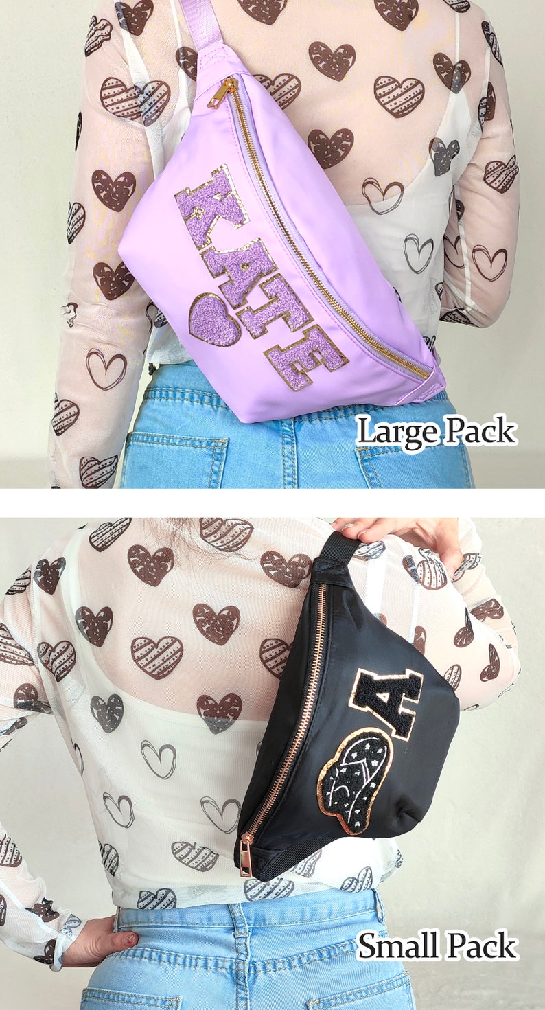 May include: Two fanny packs, one purple with the word "KAFE" in gold glitter letters and one black with a gold "A" and a heart design. Both fanny packs have gold zippers and are worn by models wearing a white shirt with brown hearts and blue jeans.