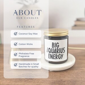 May include: A candle in a clear glass jar with a gold lid, labelled "BIG AQUARIUS ENERGY." The candle sits on a white marble coaster. The image also includes text about the candle's features: coconut-soy wax, cotton wicks, phthalate-free fragrance, and handmade in small batches.