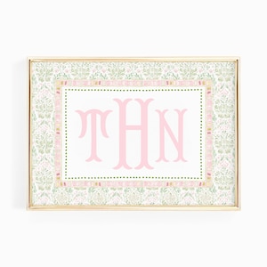 Op de afbeelding: Een rechthoekige ingelijste print met een centraal wit paneel met de roze monogramletters THN. Het ontwerp is omgeven door een rand van kleine groene stippen, een roze en geel patroonframe en een buitenste bloemmotief in groen en roze.
