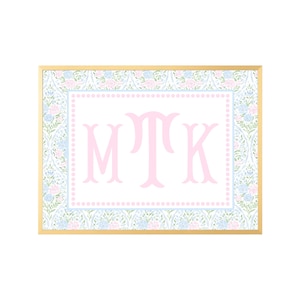 May include: A rectangular wall art piece in a gold frame featuring a central white panel with the pink monogram letters MTK. The panel is bordered by a light blue dotted line and surrounded by a floral pattern of pink and blue flowers.