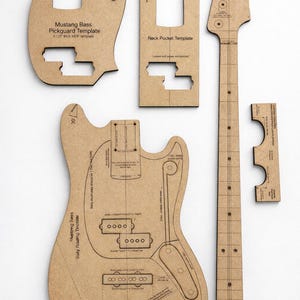 Può includere: Una collezione di modelli di chitarra in MDF marrone, tra cui un battipenna, una tasca per il manico e un modello di routing del corpo. I modelli sono etichettati con testo come "Mustang Bass" e misure. I modelli sono per un basso.