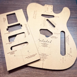 May include: Two tan guitar templates with cutouts and detailed measurements. One template is a rectangular shape with cutouts for pickups and other components. The other is a guitar body shape with various markings, including drill points and dimensions in inches.