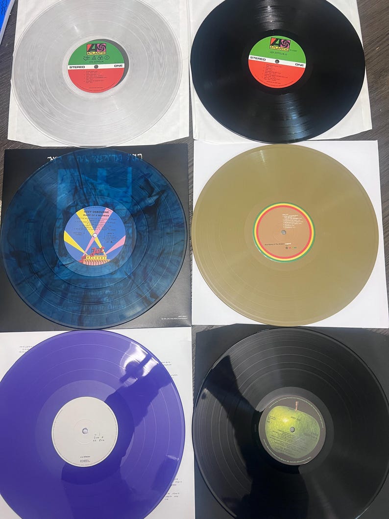 Puede incluir: Una colecci&oacute;n de seis discos de vinilo en varios colores, incluyendo transparente, negro, azul, dorado y morado. Cada disco est&aacute; en una funda de papel blanco. Las etiquetas de los discos presentan dise&ntilde;os y texto coloridos.