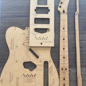 May include: A guitar routing template set made of light brown wood. The set includes a body template, neck, and other pieces with measurements in inches. The body thickness should be 1.75 inches. The template is labeled "Guitar Routing Template".
