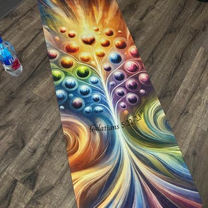 Puede incluir: Una colorida esterilla de yoga con un diseño de árbol de la vida y el texto "Galatians 5:22-23". El árbol está hecho de círculos coloridos y tiene un corazón en la parte superior.