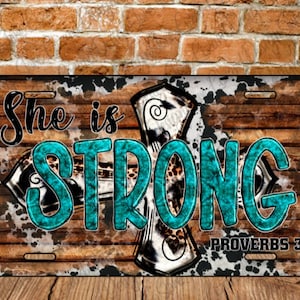 Puede incluir: Un fondo de madera rústico con un patrón de piel de vaca y una cruz turquesa con las palabras "She is STRONG" y "PROVERBS 31:25" en letras negras.