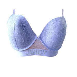 May include: A light purple bra with a floral lace overlay. The bra has adjustable straps and a band with the word "JUICY" spelled out in silver rhinestones. The bra is set against a white background.