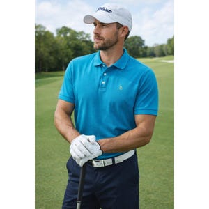 May include: A man wearing a white Titleist baseball cap and a turquoise polo shirt with a small penguin logo. He is holding a golf club and wearing white golf gloves and a white belt. The background is a green golf course.