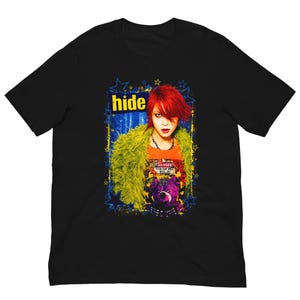 May include: A black short-sleeve t-shirt featuring a graphic print of the musician hide with bright red hair, wearing a lime green fuzzy jacket. The design includes the text hide, a purple teddy bear, and blue star accents.