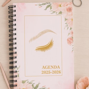 May include: A spiral-bound agenda for 2025-2026 with a pink floral design. The cover features an illustration of an eyebrow and eyelashes, with the word "AGENDA" and the years printed in gold. A pair of scissors and tweezers are on the surface.