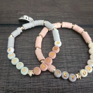 May include: Two beaded bracelets with the names "Zach" and "Brya" on one and "Hey" and "Driv" on the other. The beads are in shades of pink, white, and green.