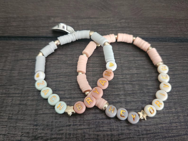 May include: Two beaded bracelets with the names "Zach" and "Brya" on one and "Hey" and "Driv" on the other. The beads are in shades of pink, white, and green.