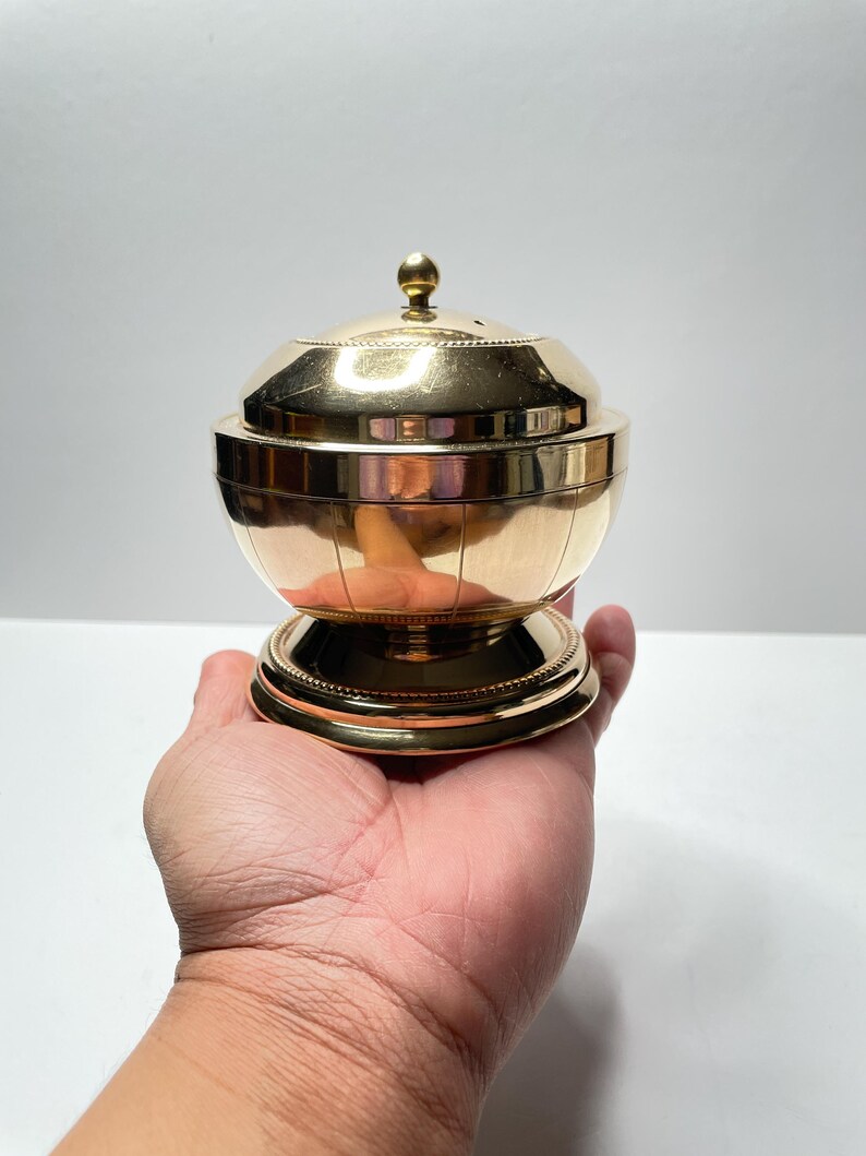 Peut inclure: Un br&ucirc;leur d'encens en m&eacute;tal dor&eacute; avec un couvercle rond et une base. Le br&ucirc;leur a un motif d&eacute;coratif sur le couvercle et la base.