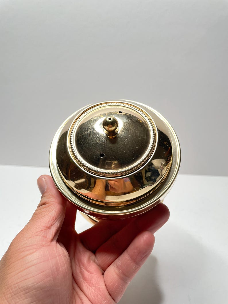 Peut inclure: Couvercle en m&eacute;tal dor&eacute; avec un petit bouton sur le dessus. Le couvercle a une bordure d&eacute;corative autour du bord.