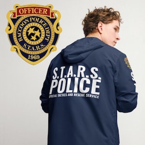 May include: A navy blue jacket with a white "S.T.A.R.S. POLICE" logo on the back. The logo is surrounded by the text "SPECIAL TACTICS AND RESCUE SERVICE". The jacket has a hood and a zip closure. A gold badge with the text "RACCOON POLICE DEPT. S.T.A.R.S. 1969" is visible on the left side of the image.