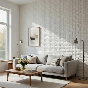 May include: A modern living room with a light gray sofa, wooden coffee table, and a neutral-toned rug. The white textured wall and framed artwork add to the room's contemporary design. Two floor lamps and a vase of flowers complete the decor.