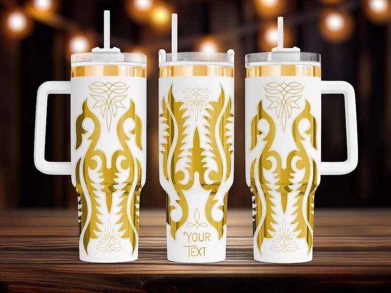 May include: Three white insulated tumblers with gold decorative patterns and handles. Each tumbler has a white lid, a straw, and the words "YOUR TEXT" printed on the front. The tumblers are on a wooden surface.