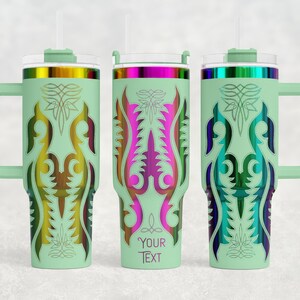 May include: Three mint green insulated tumblers with handles, lids, and straws. Each tumbler features a unique, colorful, symmetrical design. The middle tumbler has the text "YOUR TEXT" at the bottom. The designs include gold, pink, blue, and green.