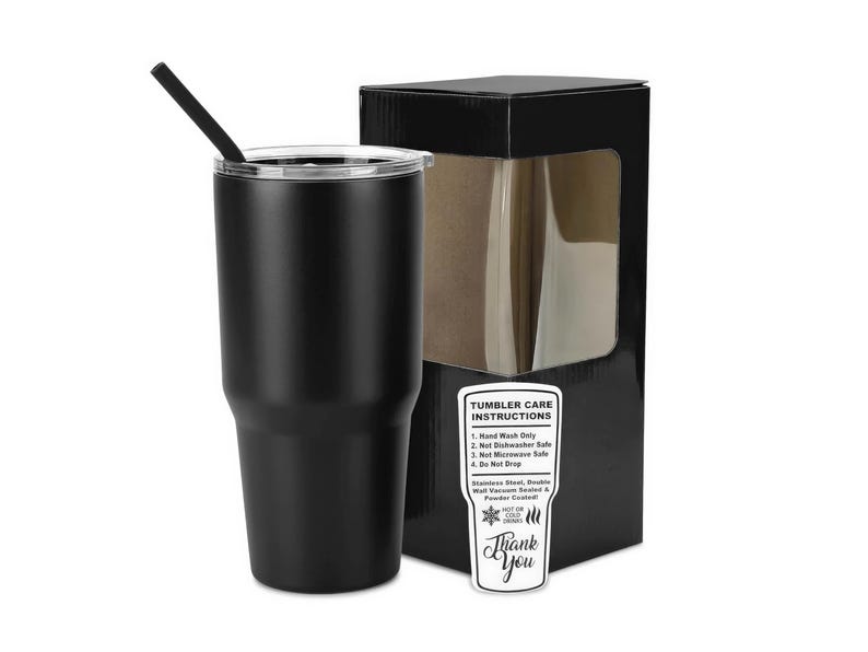 Op de afbeelding: Een matzwarte roestvrijstalen beker met een doorzichtig deksel en een zwart rietje, vergezeld van een zwarte geschenkdoos met een venster en een wit label met onderhoudsinstructies: Hand Wash Only, Not Dishwasher Safe, Not Microwave Safe, Do Not Drop.