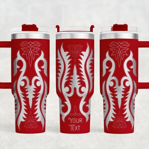 May include: Red insulated tumbler with a silver ornamental design and a handle. The tumbler has a clear lid, a red straw, and the text "YOUR TEXT" at the bottom. The design is symmetrical and features floral and leaf-like patterns.