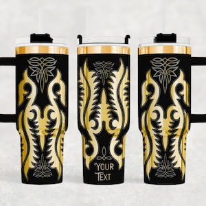 May include: Black and gold insulated tumbler with a handle, straw, and lid. The tumbler features a gold ornamental design on a black background. The design includes a space for custom text. The tumbler is designed to keep beverages cold or hot.