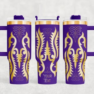 May include: Purple travel tumbler with a gold ornate design and a handle. The tumbler has a gold rim and a clear lid with a straw. The text "YOUR TEXT" is printed on the tumbler.